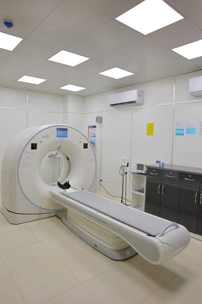 A modern CT scan machine in a well-lit, sterile hospital room for diagnostic imaging.