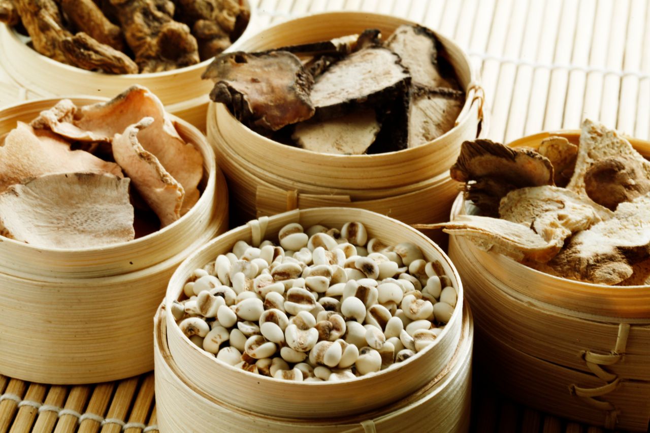 Does Traditional Chinese Medicine (TCM) really work? From above many wooden containers filled with assorted dried mushrooms with condiments and raw cashew nuts placed on bamboo mat